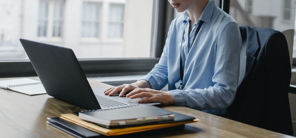 Crop female employee working on laptop in office