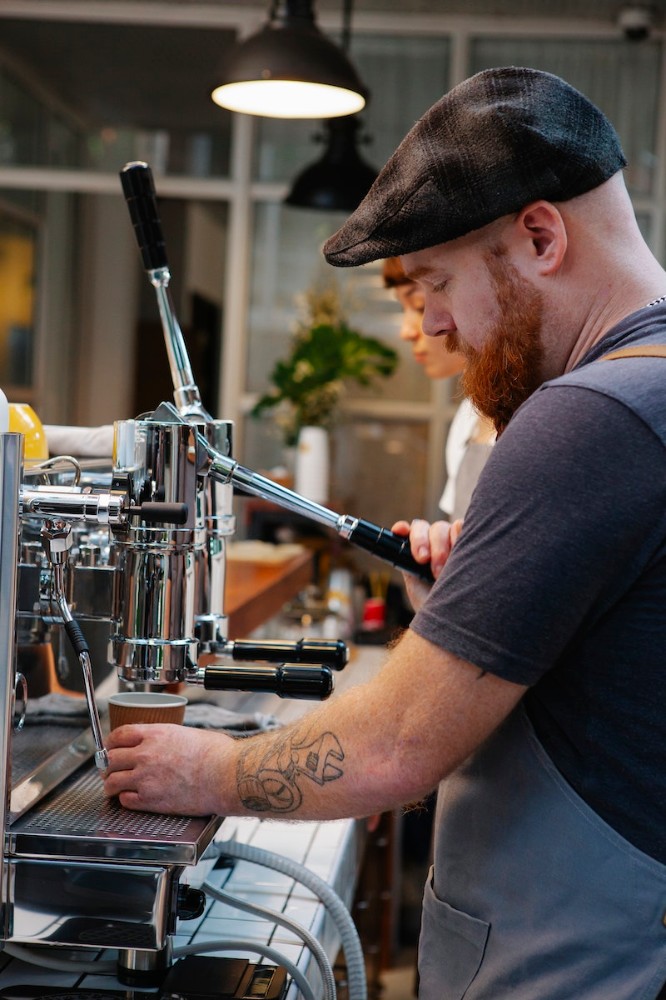 Brutal bearded bartender preparing coffee with machine